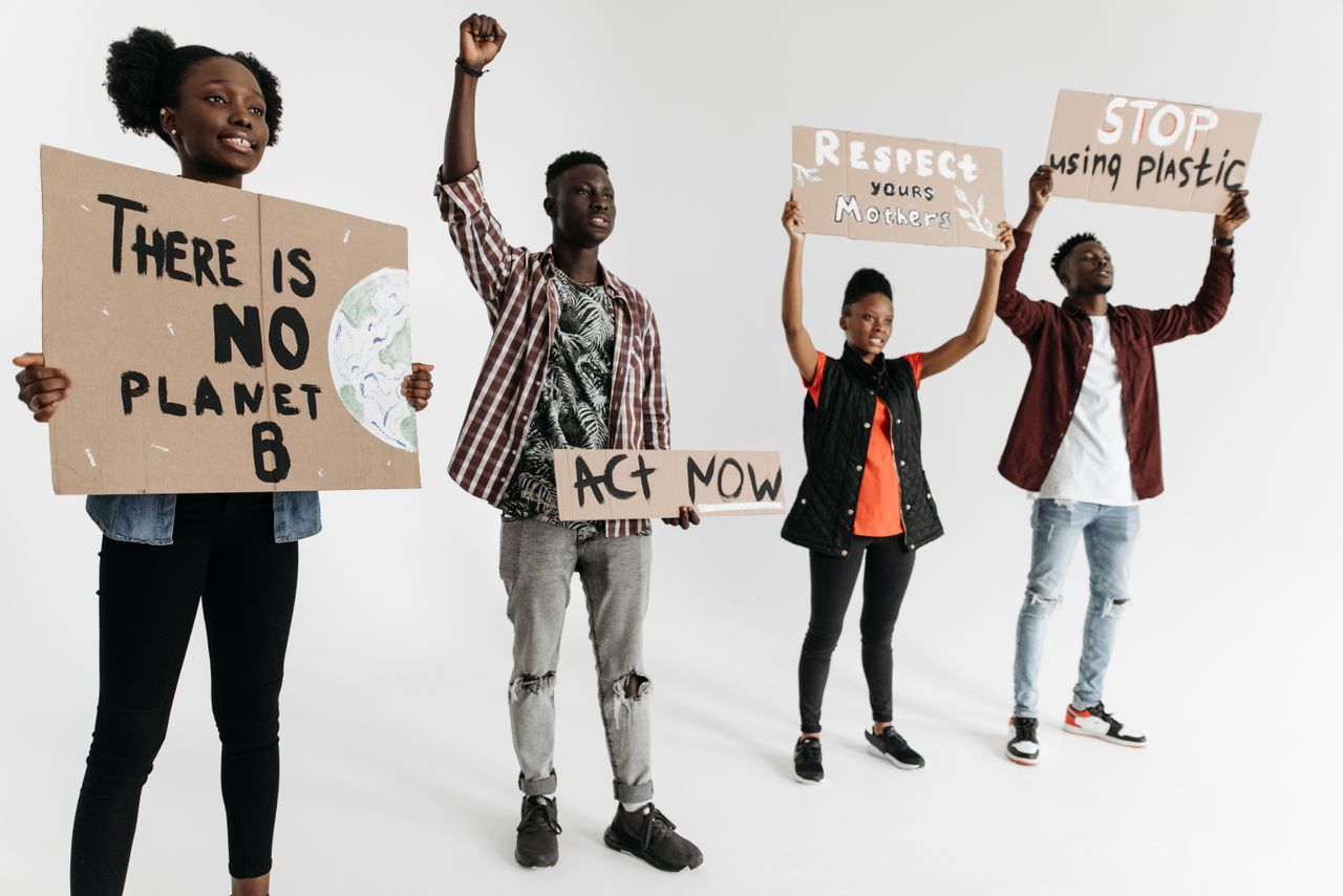 about-us Diverse group of young adults holding environmental protest signs indoors on a white background.